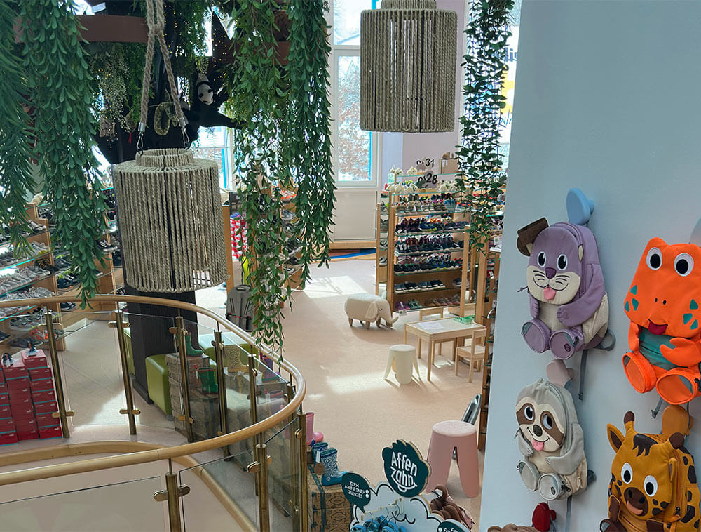 Innenansicht Schreiber Kids Adventureland Wilnsdorf:
Baum der Wünsche, bunte Tier-Rucksäcke an der Wand und
gemütliche Mal- und Bastelecke im Familien Erlebnisstore
Siegerland